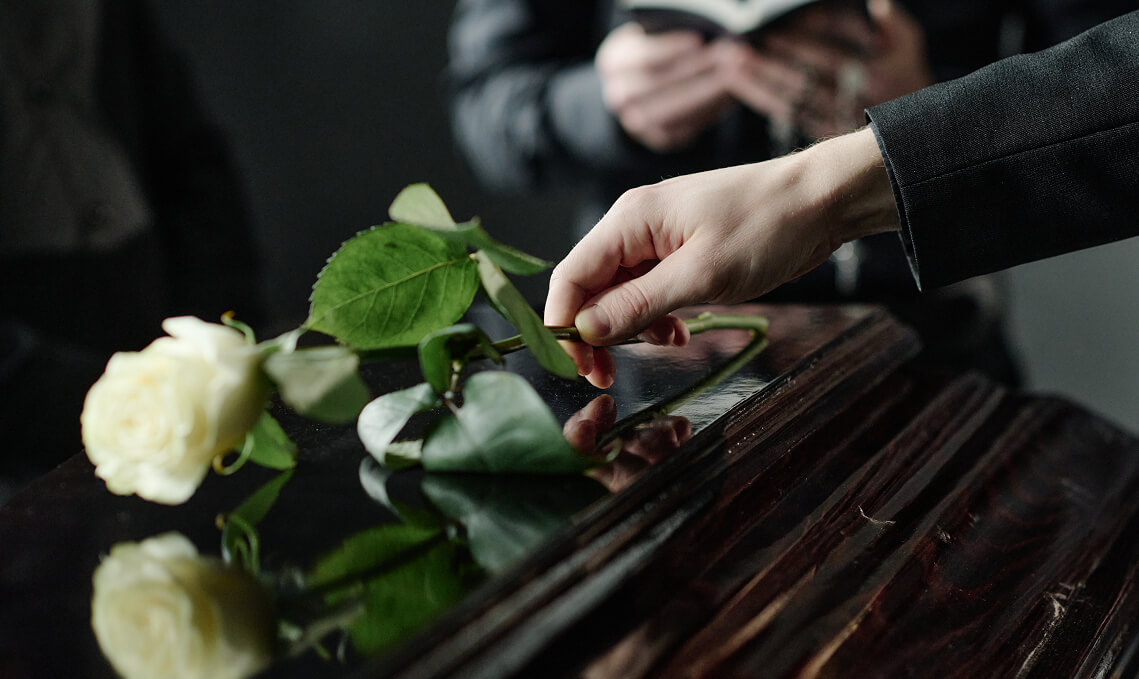 White rose being placed on a coffin during a funeral service